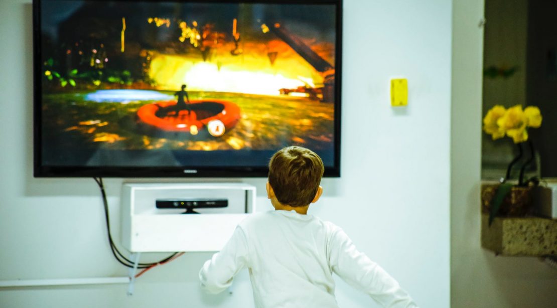 boy standing in front of flat screen tv